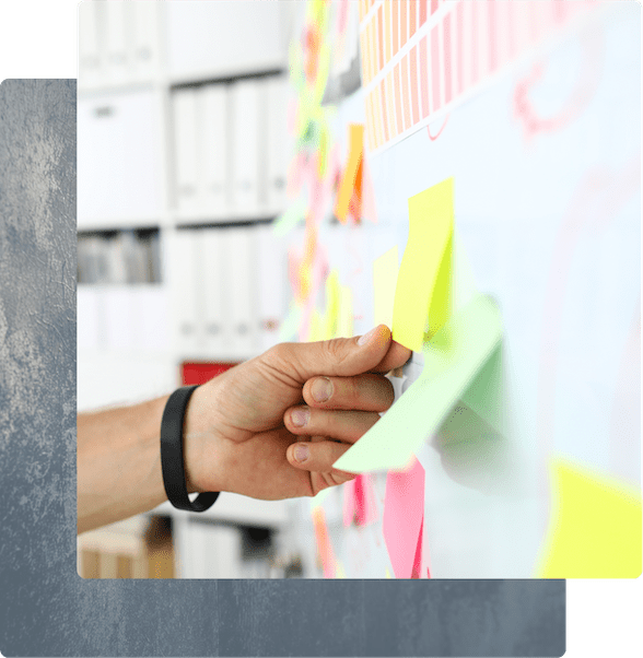 A person’s hand placing a yellow sticky note on a whiteboard during a brainstorming session.