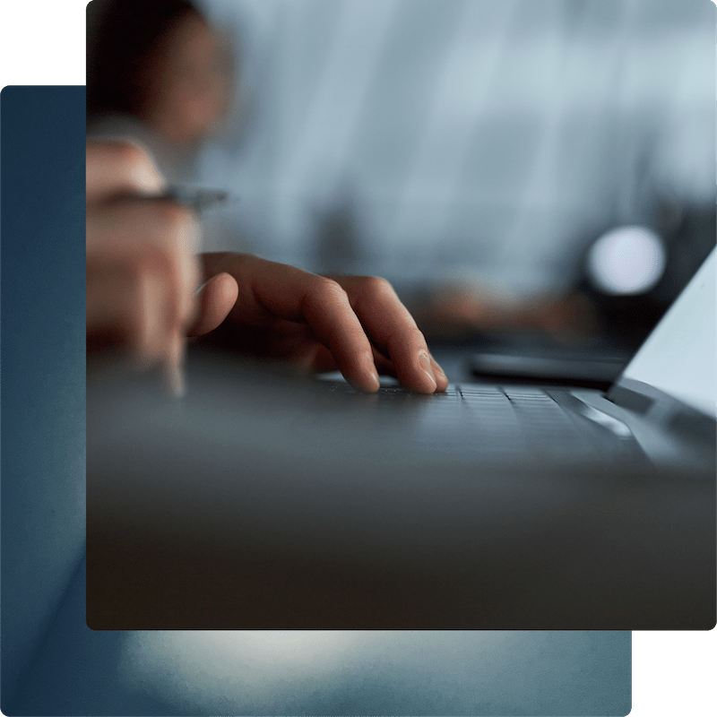 A shallow-focus shot of a professional using a computer in a dark, modern environment.