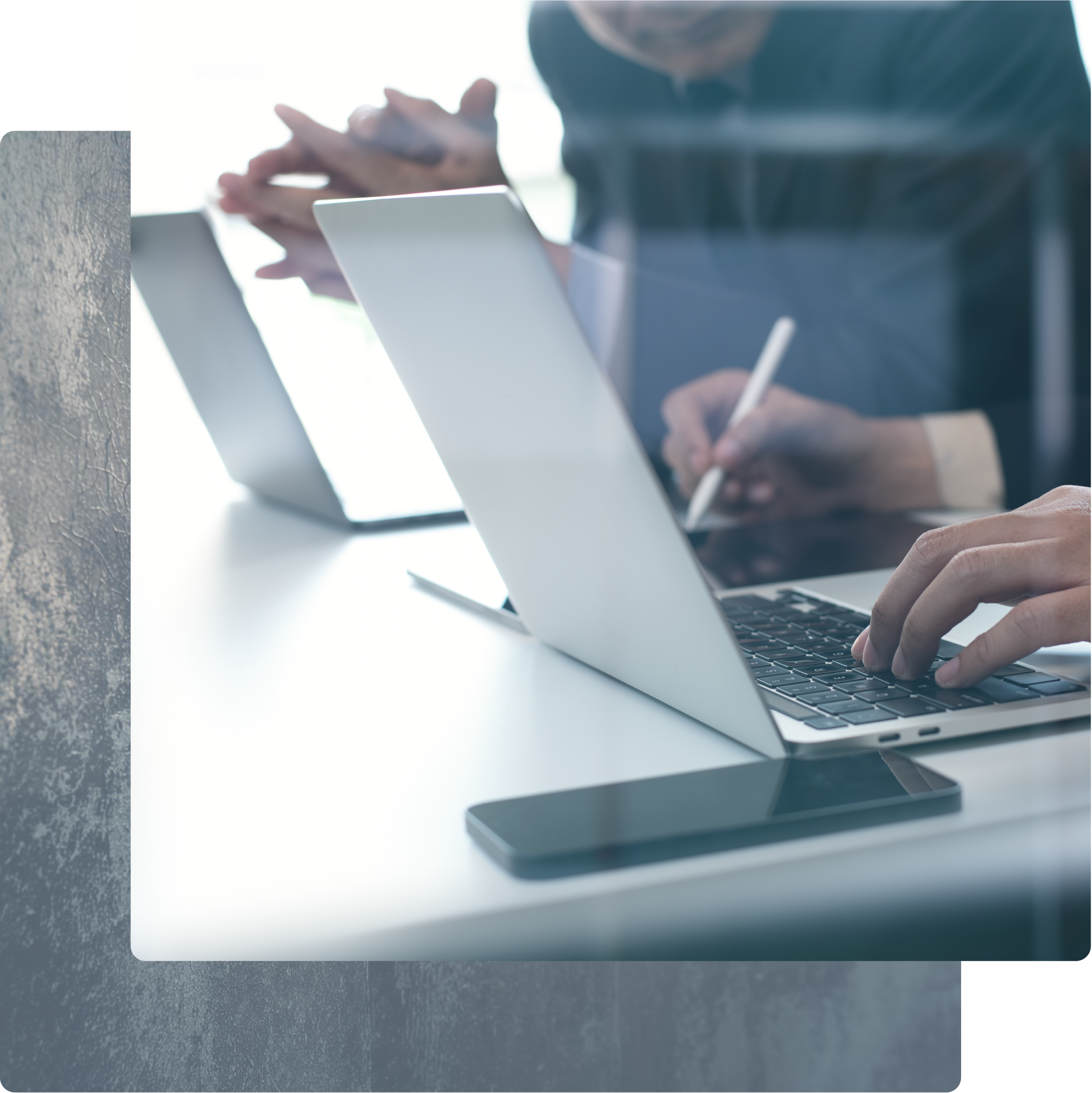 Close-up of hands typing on a laptop and using a stylus on a tablet.