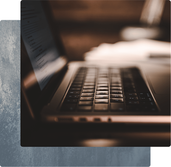 A side-view of an open laptop on a desk with warm lighting.