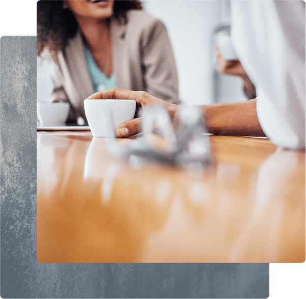 Professionals having a casual conversation over coffee in a bright office setting.