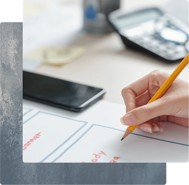 Close-up of a designer's hand drafting a mobile app layout during the low-fidelity prototyping phase.