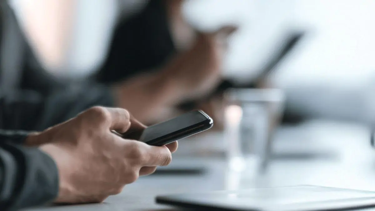 person looking at phone while sitting in meeting