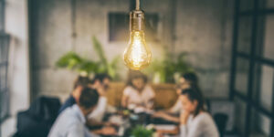 Group of marketers working at a table, with a bright light bulb over their heads.